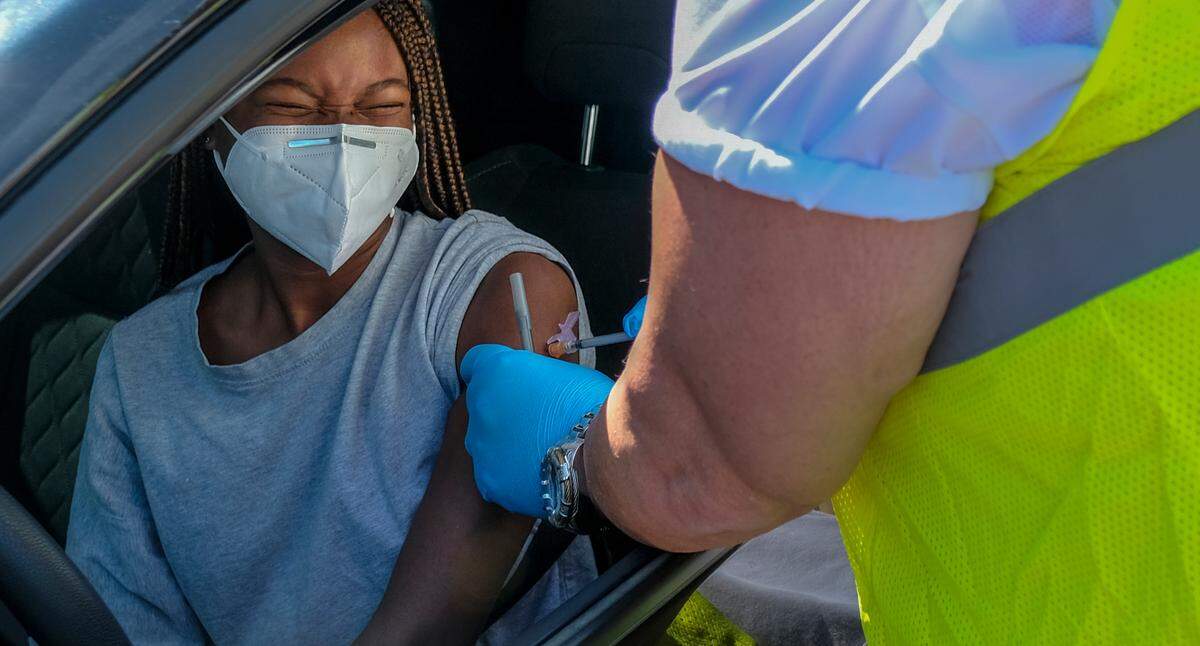 Rachel Joyner, 21, winces as Donald Bodiker, a registered nurse from Beaufort Memorial Hospital, administers the first dose of the Pfizer-BioNTech vaccine against COVID-19 on Aug. 12, 2021 at Bluffton Middle School. “Hey, that wasn’t bad at all,” Joyner said after receiving the shot. The Beaufort County School District and Beaufort Memorial Hospital partnered to have drive-thru vaccine clinics at schools.