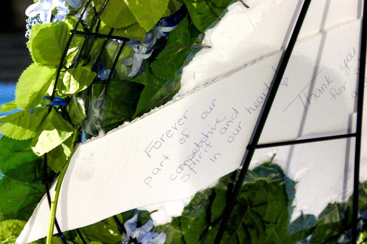 A handwritten note on the back of a floral wreath reads, “Forever part of our competitive spirit and in our hearts!” at the celebration of life for athletic director Joe Monmonier on July 14, 2025 at Hilton Head Island High School.