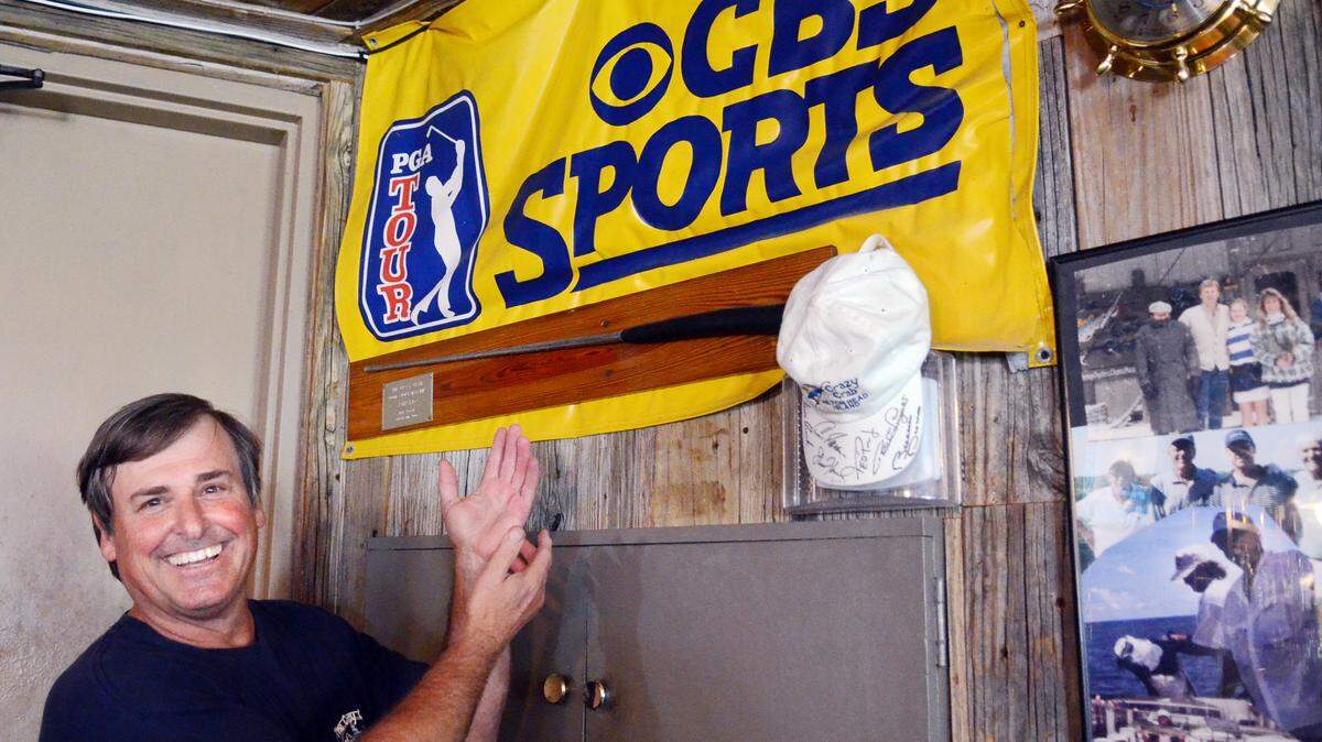 Harbour Town Crazy Crab bartender Chris Wagner shows off a CBS Sports banner April 7, 2015. The banner hangs on the wall of the bar after it was rendered as payment by someone who couldn't pay his tab.