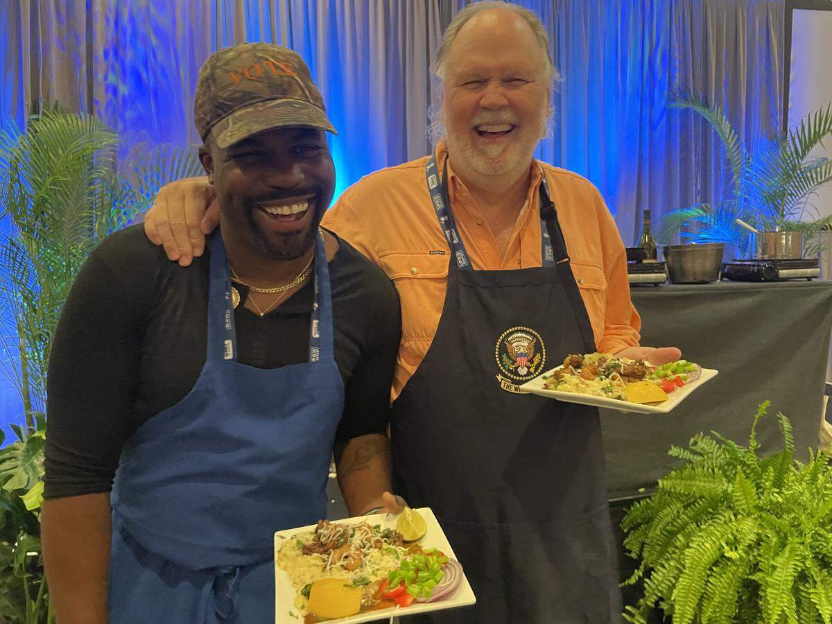 Charleston Rep. JA Moore (left) and Hilton Hed Rep. Jeff Bradley (right) show off their finished plates of shrimp and grits with sausage gravy.