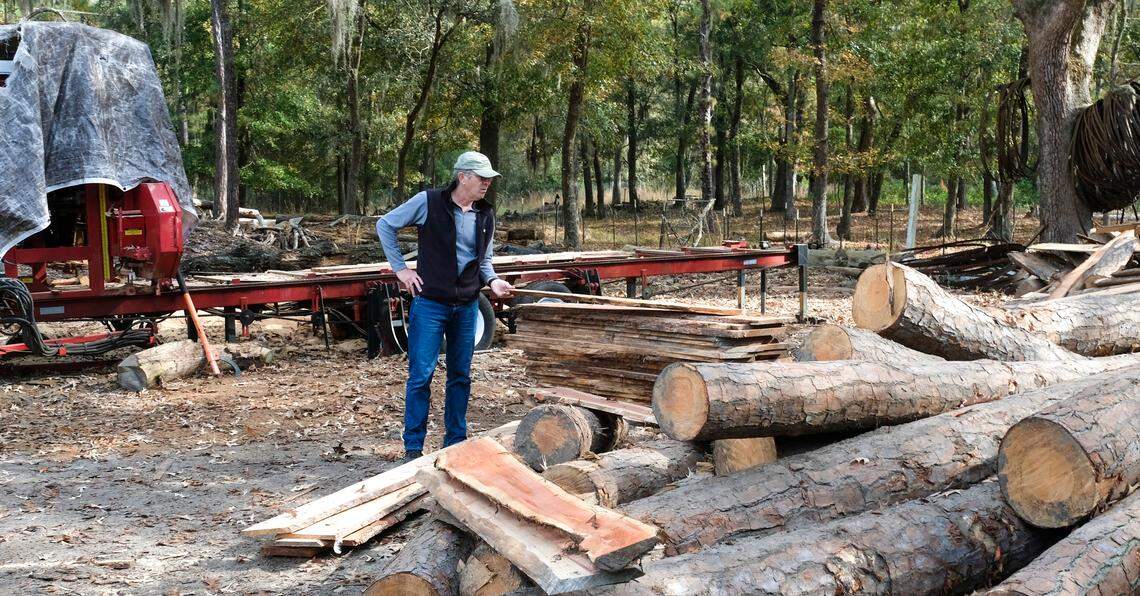 John Tarrant, a Daufuskie Community Farm member, admires planks of cedar that were milled with the hydraulic sawmill that sits behind him on Dec. 6, 2021 on Daufuskie Island. Carpenters are able to cut hardwood with the sawmill that is used in the structures they are building for a future artisan village if they can raise the $236,000 to buy the 8-acre site.