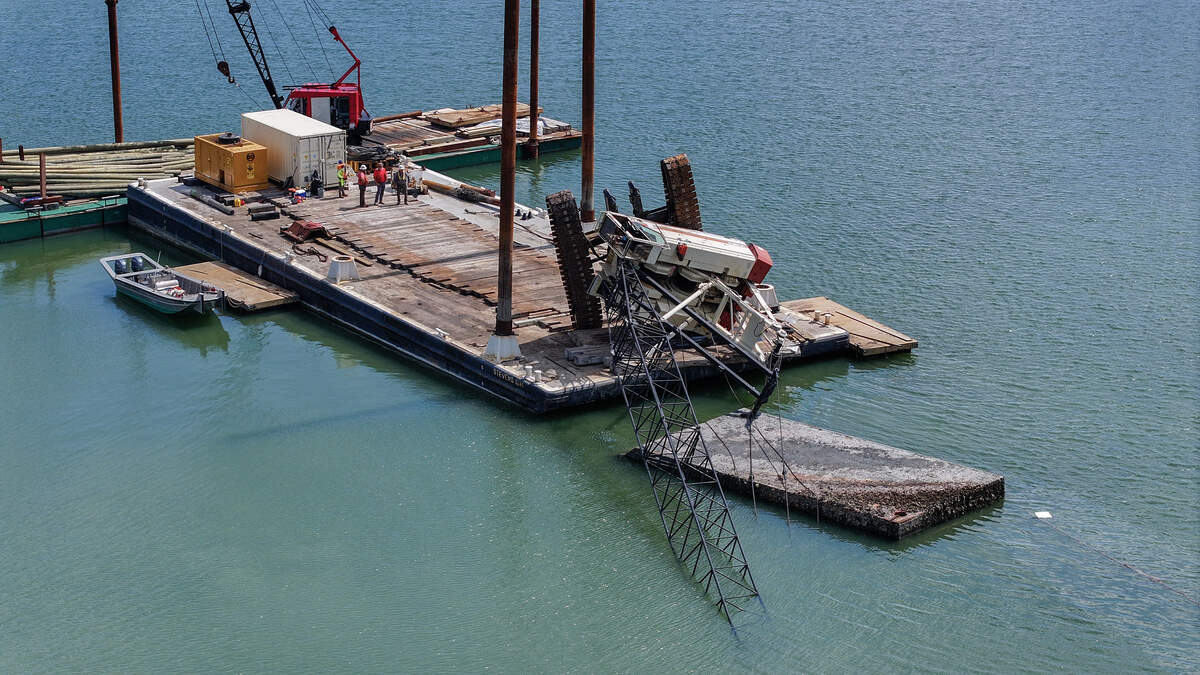 A crane sits precariously tipped over on a barge as photographed on June 30, 2026, in Mackay Creek near the bridges to Hilton Head Island. According to on-scene members of the United States Coast Guard, operators of the crane likely misjudged the counterweight as they were trying to remove the smaller barge as seen in the foreground.