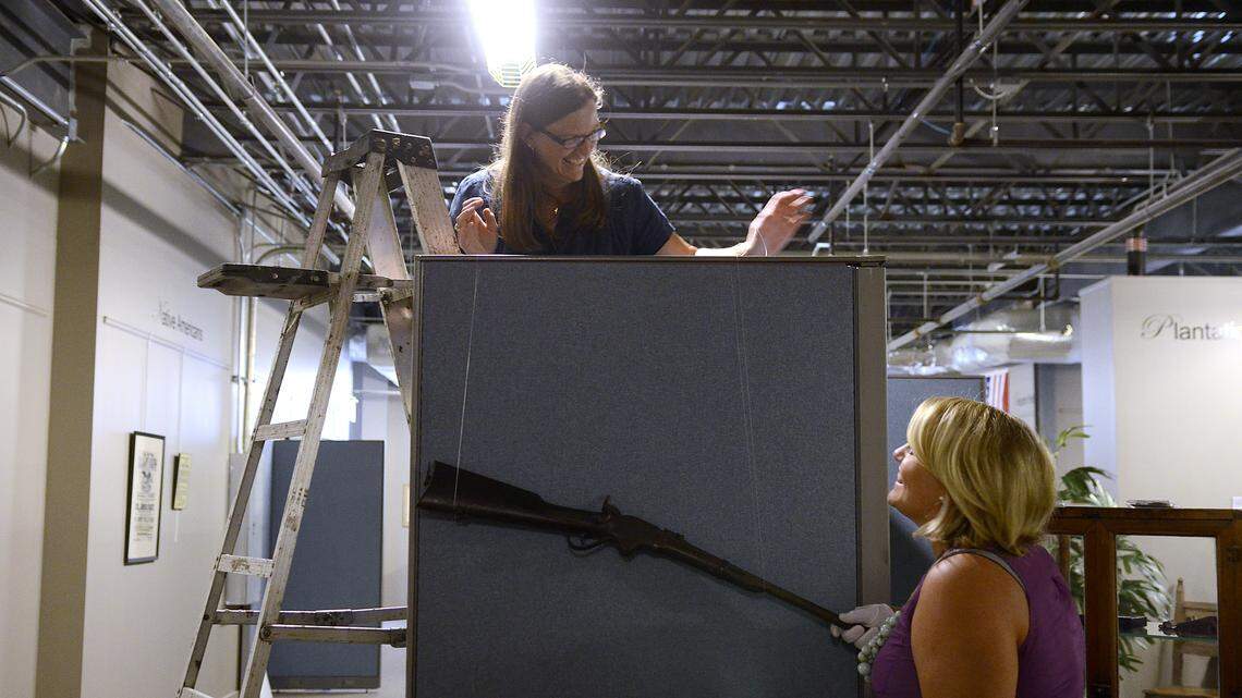 Libby Holloway, left, and Anna Schafer, right, both Beaufort History Museum board members, share a laugh while hanging a Civil War era gun on Thursday afternoon while setting up the new exhibit on the First South Carolina Colored Troops in the Beaufort History Museum at City Hall in Beaufort.  The exhibit will open on Sept. 5 and will run through December.  To see a video about the exhibit go to islandpacket.com/local-news-videos.