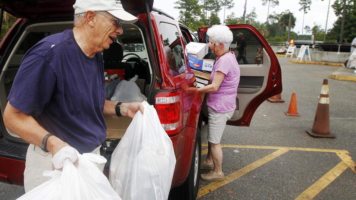 FILE: Richard and Peggy Geraghty, of Bluffton, carry trash and recyclables from their vehicle to dump at the Bluffton Convenience Center at 104 Simmonsville Road on Aug. 1, 2014. Beaufort County's 11 trash and recycling centers reduced operating hours beginning Oct. 4, part of budget cuts county officials say were necessary to avoid a tax increase. Most centers went from being open 7 a.m. to 7 p.m. seven days a week to 9 a.m. to 7 p.m. six days a week.