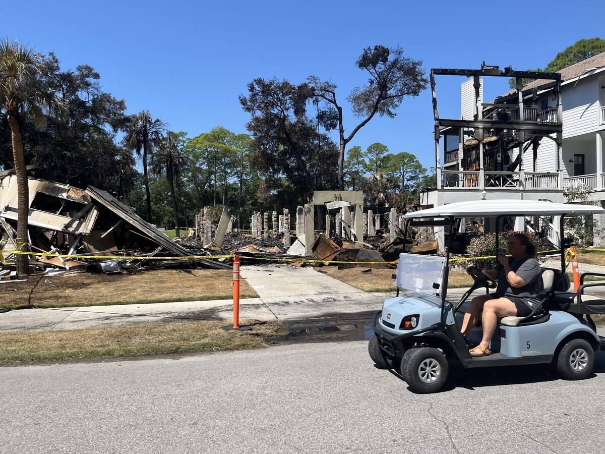 A golf cart driver passes by houses on Bonito Road on Fripp Island Monday. Three houses were destroyed by a Saturday fire, which also claimed the life of a 70-year-old man.