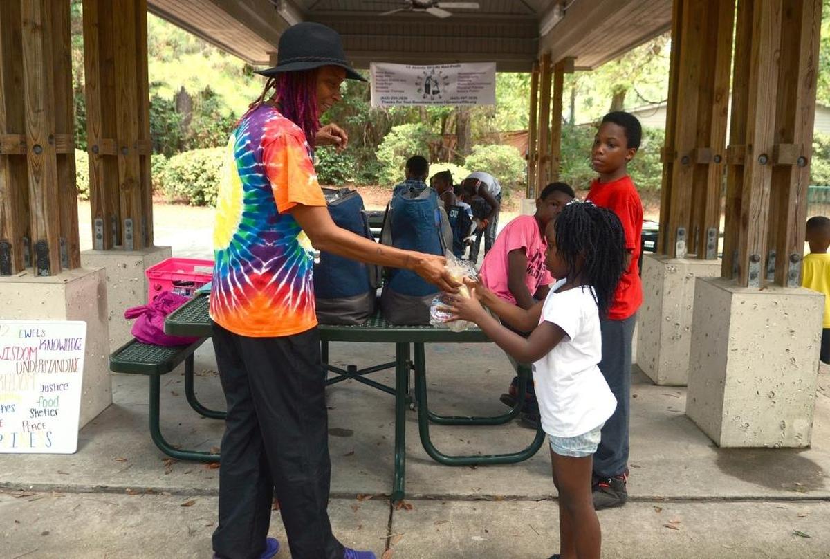 Rochelle Williams, left, gives Elajah Jones-Waters, 6, a lunch provided by 12 Jewels of Life on Wednesday, August 10, 2016, under the pavilion at Green Shell Park on Hilton Head Island. The non-profit group, headed by Williams, has been at the park every week day during the summer to offer free lunches to children in the area.