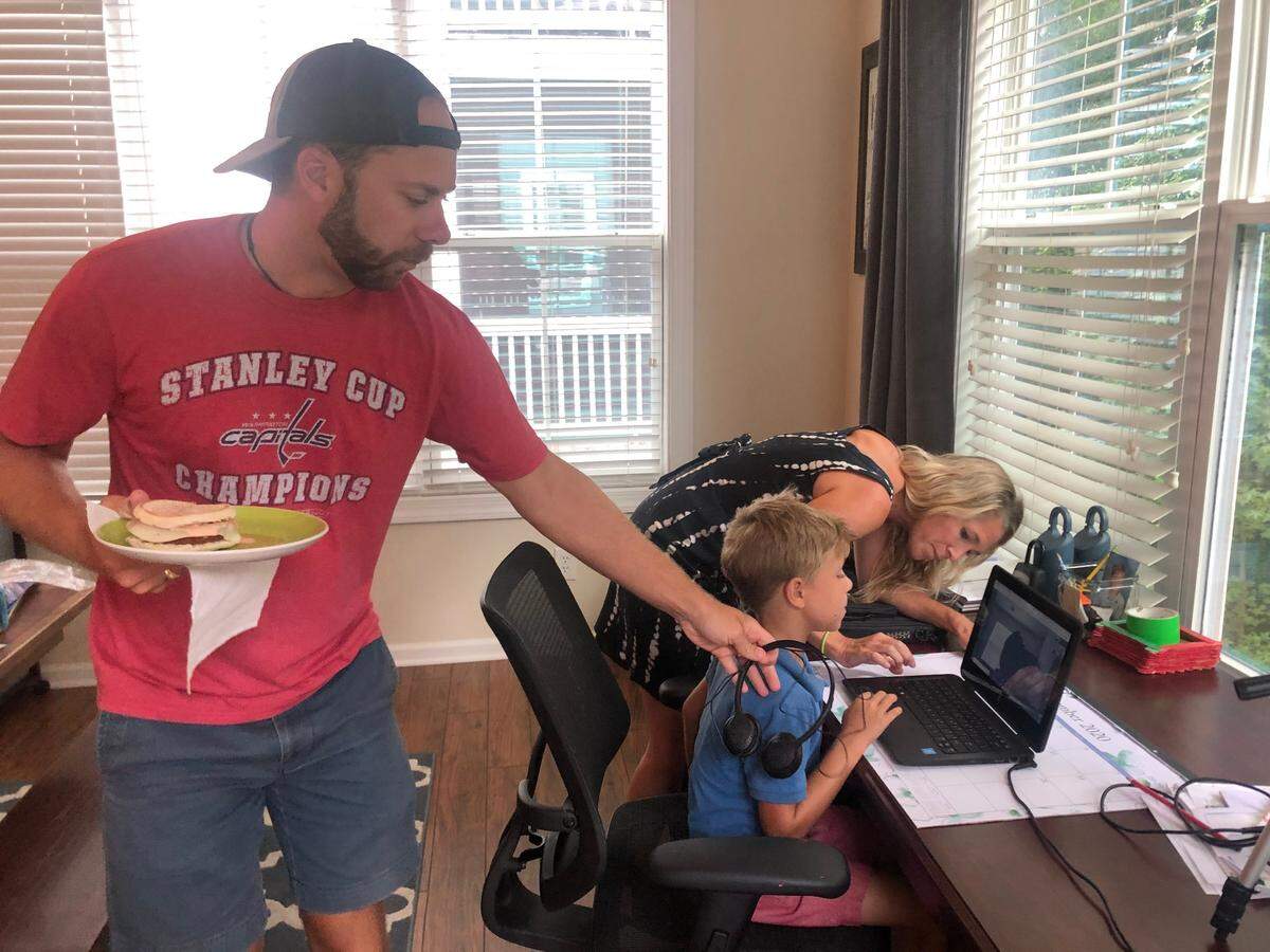 Alex Smith lets his grilled sandwich get cold as he hands his son, Landon, headphones and his wife, Sarah, tries to find the jack on his computer. The family has a third grader and first grader in virtual classes.