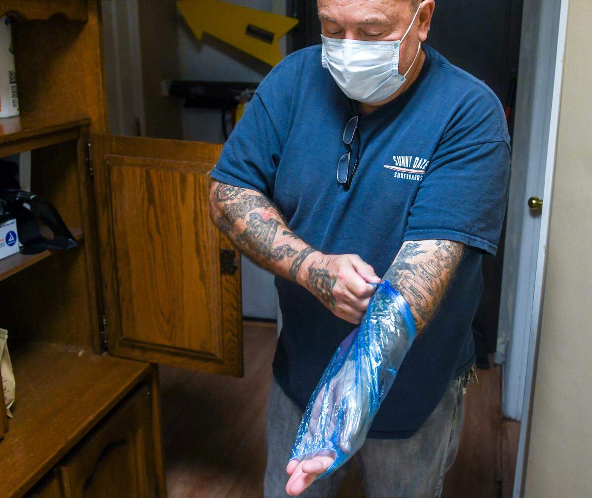 Mark Smith, owner of Bluffton’s Sugar Shack Canvas & Ink, displays a disposal protective arm sleeve, one of several new pieces of gear to reduce contact. While face masks are mandatory for the artists, “We leave it up to the customer,” Smith said of how much protective gear tattoo artists will wear. “If they (customers) want, we have disposable arm sleeves and aprons” that can be worn to minimize contact. “Nobody wants to take it (the coronavirus) home to our families.”