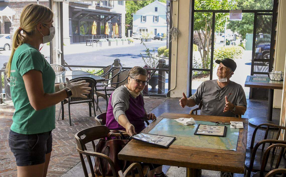 Sun City Hilton Head residents Cathy and John Burckhardt order lunch at Captain Woody’s Bar & Grill as Casey Brinkley, left, verifies their order on Monday, May 4, 2020 in Bluffton’s Promenade. Monday marked the first day that restaurants could serve customers in outdoor spaces if certain precautions were met to help stave off the spread of the coronavirus.