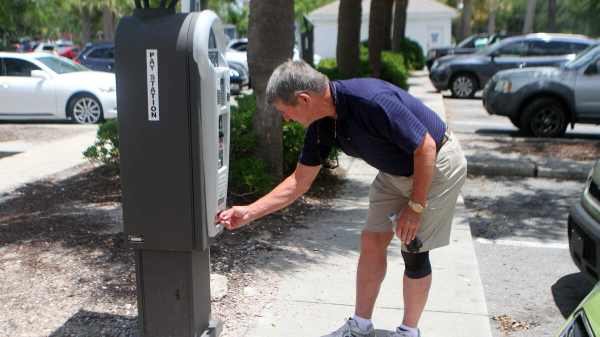 Robert Cook, of Kansas City, Mo., removes the receipt for two hours of free parking from a pay station in downtown Beaufort the afternoon of June 11, 2015.