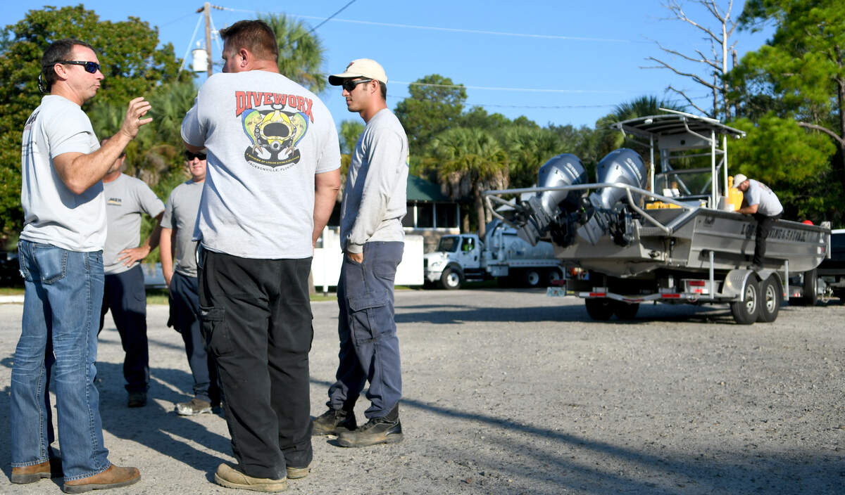 Bernie Reagan, left, regional manager for Moran Environmental Recovery of Savannah, Ga. talks to Diveworx Division team members of Logan Diving and Salvage based out of Jacksonville, Fla. on Thursday morning at Alljoy Boat Landing in Bluffton. The two companies, contracted by the United States Coast Guard, are participating in the recovery of any petroleum that remains in the holds of the “Miss Annie,” a shrimp boat partially sunk in the May River.