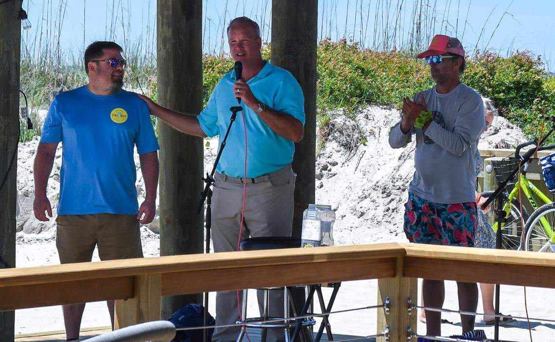 As part of the opening celebration, Jay Wiendl, center, general manager of Beach House Hilton Head Island, introduces Brent Kloster, left, bartender for Hudson’s Seafood House on the Docks on Thursday, May 30, 2024, at Coligny Beach. Kloster was guest bartending at the Tiki Hut to raise money for Hilton Head’s The Deep Well Project during a “Tiki-Thon” fundraising shift.