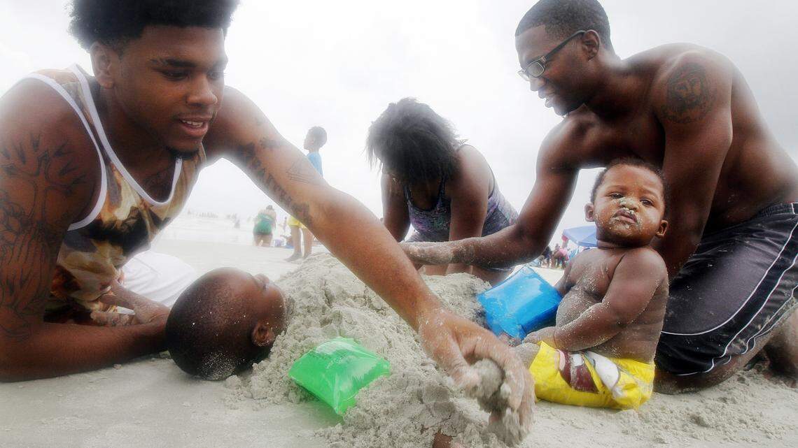 Theophil Syslo, Staff photo 
From left, Marion Nealy, 18, of Rincon, G.A., Chrishonda Pendleton, Monterious Neal, 27, and Myron Neal, 10-months, bury Javorries Jr. Pendleton, 5, in sand while at Coligny Beach Park on July 5, 2014.