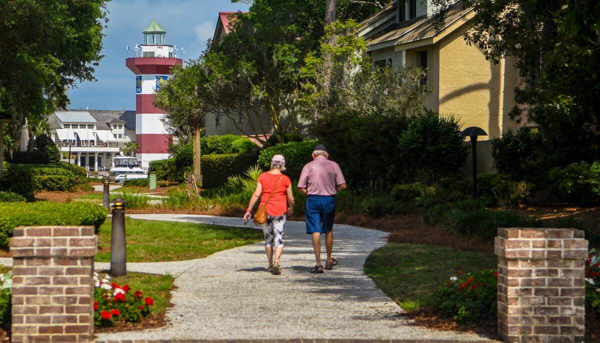 A couple walks down the path from the clubhouse toward the lighthouse at the Harbour Town Yacht Basin on Thursday, April 6, 2023, at Sea Pines on Hilton Head Island.
