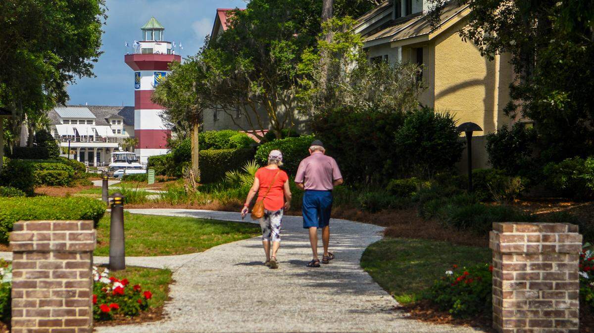 A couple walks down the path from the clubhouse toward the lighthouse at the Harbour Town Yacht Basin on Thursday, April 6, 2023, at Sea Pines on Hilton Head Island.