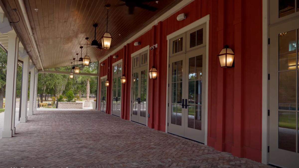 A covered patio with lighting and outdoor ceiling fans are on the north side of The Barn at New Riverside.