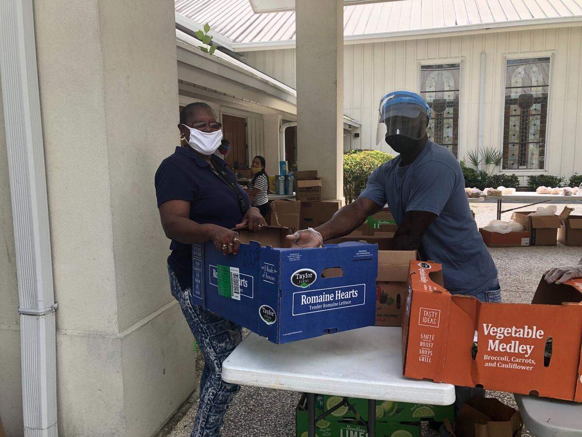At Bluffton Community Soup Kitchen, volunteer and Bluffton Mayor Pro Tem Fred Hamilton (right) helps Patricia Garner (left) fill her box with food to distribute to the elderly.