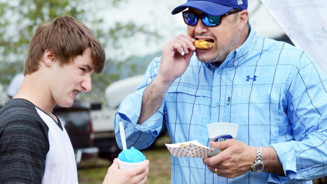 Steve Green, of Atlanta, digs into a Wild West wing from Wild Wings Cafe as his son, Jackson Green, enjoys a snow cone at the 20th annual WingFest on Saturday.