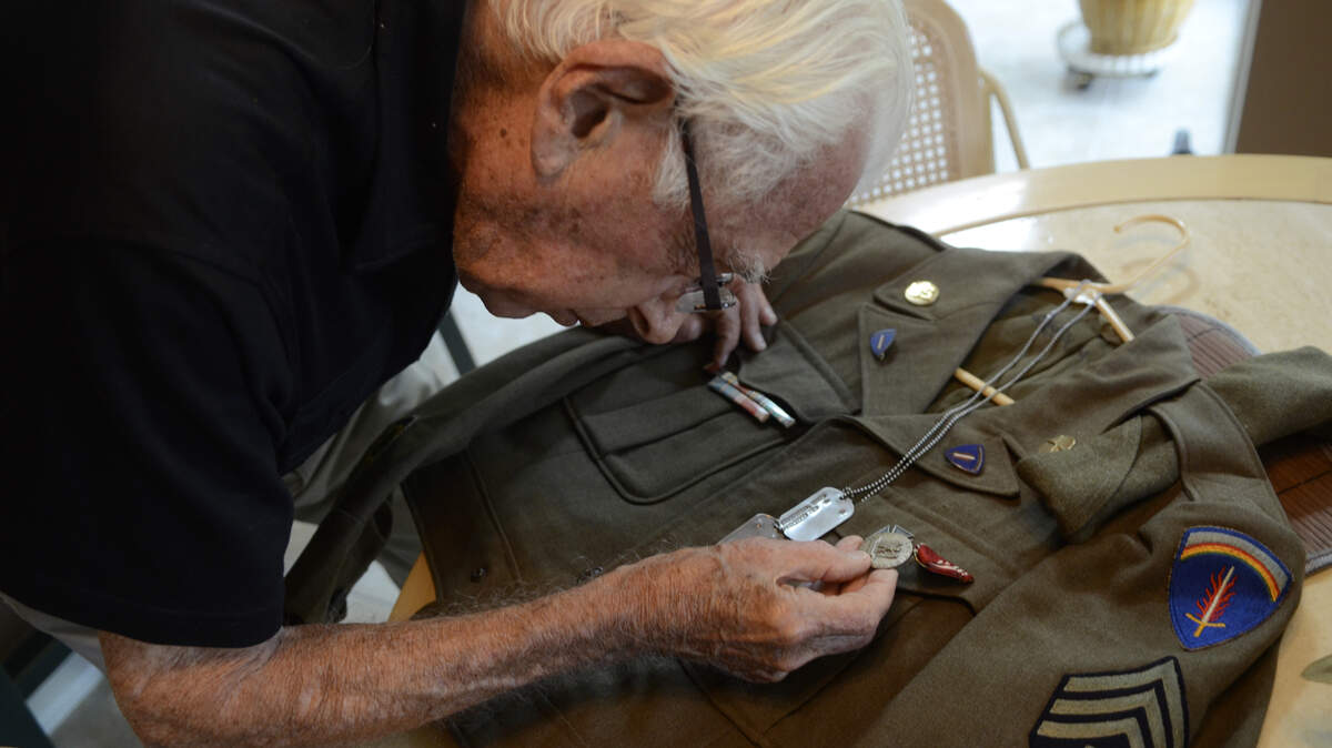 Irwin Lindenbaum, a World War II veteran from Bluffton, identifies the different adornments on his uniform from World War II at his home June 5, 2014.