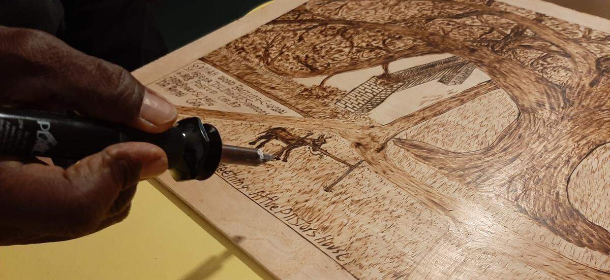 The Rev. Johnnie Simmons uses a wood burning tool to create his art that focuses on life in the Lowcountry.