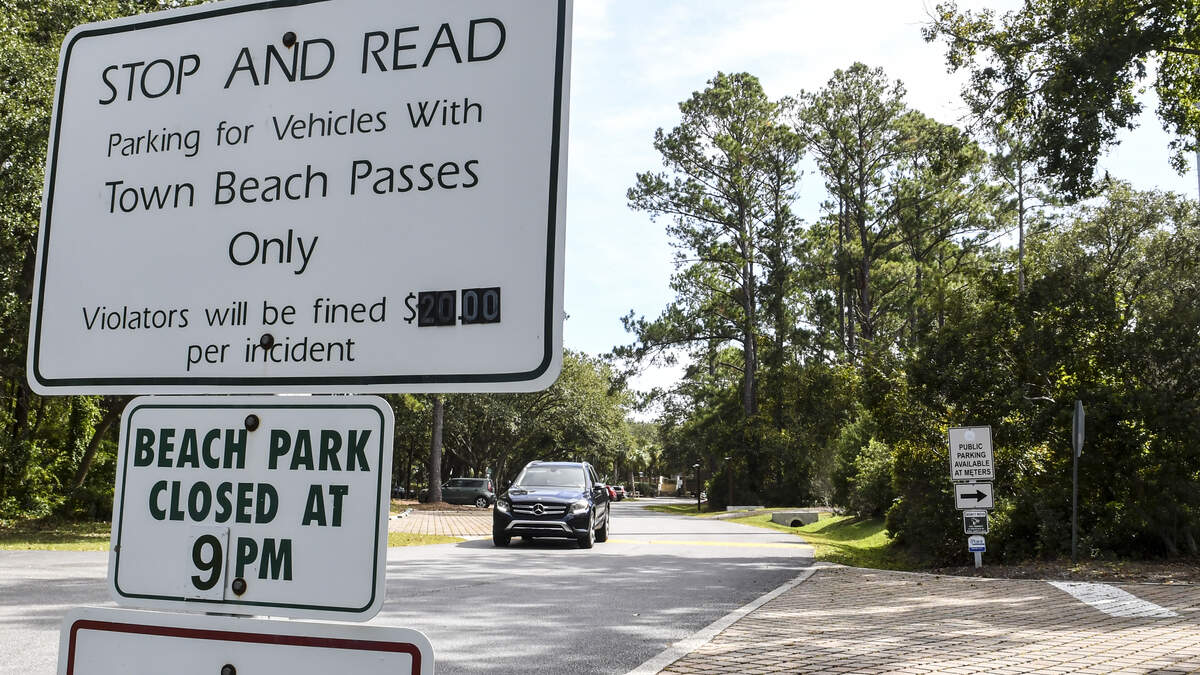 A sport utility vehicle leaves the beach pass parking side of Islanders Beach Park on Friday afternoon as a sign warns visitors without a pass at the Hilton Head Island beach park of a $20 fine. Public metered parking is available when entering the parking lot for those without a town pass.