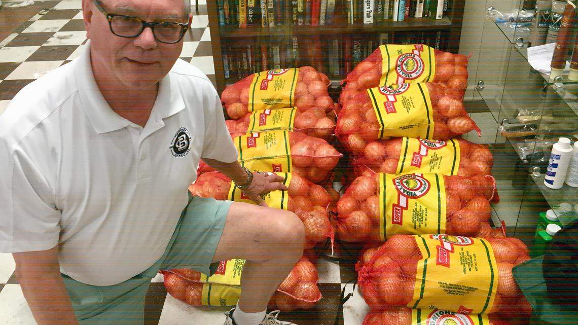 Johnny Harvey with 25-pound bags of Vidalia onions he sells for the Rotary Club of Beaufort at Harvey's Barber Shop.