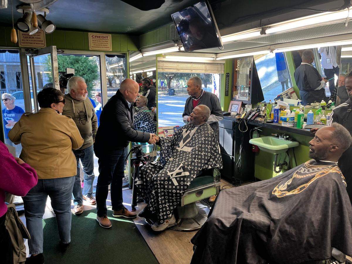 Mitch Landrieu, the national co-chair of the Joe Biden-Kamala campaign, arrives at Singleton’s Barber Shop Tuesday for a “we go first” tour in advance of Saturday’s Democratic primary in South Carolina, as Kenneth Singleton Sr., the owner of the shop, trims the hair of a customer. The state’s Democratic primary is the first in the nation.