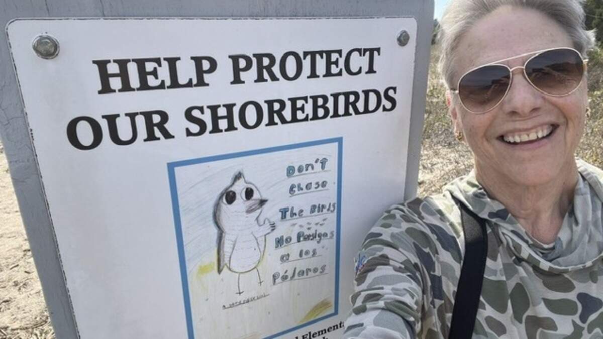Lois Lewis poses at a Hilton Head Island beach by a sign that was illustrated by island school students.