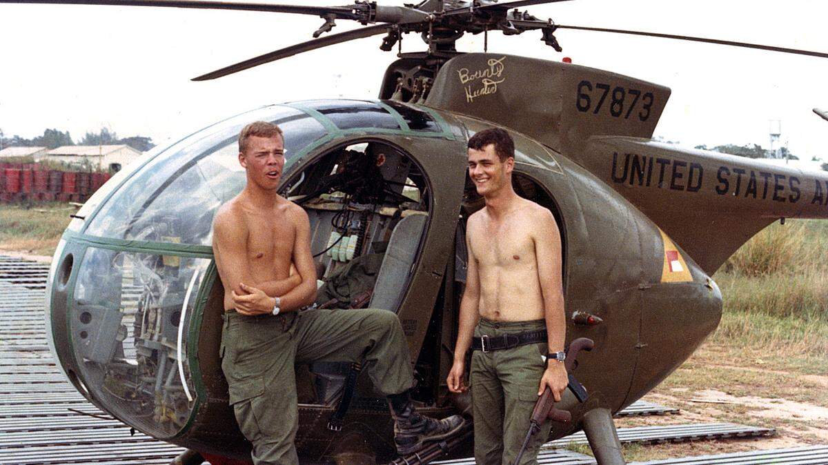 Bob Buffington, left, and Dave Mitchell on a break between two-hour searches in Vietnam aboard a U.S. Army Hughes OH-6 Cayuse light observation helicopter. To watch a video excerpt of Buffington explaining their daily objective, go to: http://bit.ly/1gf1c6W.