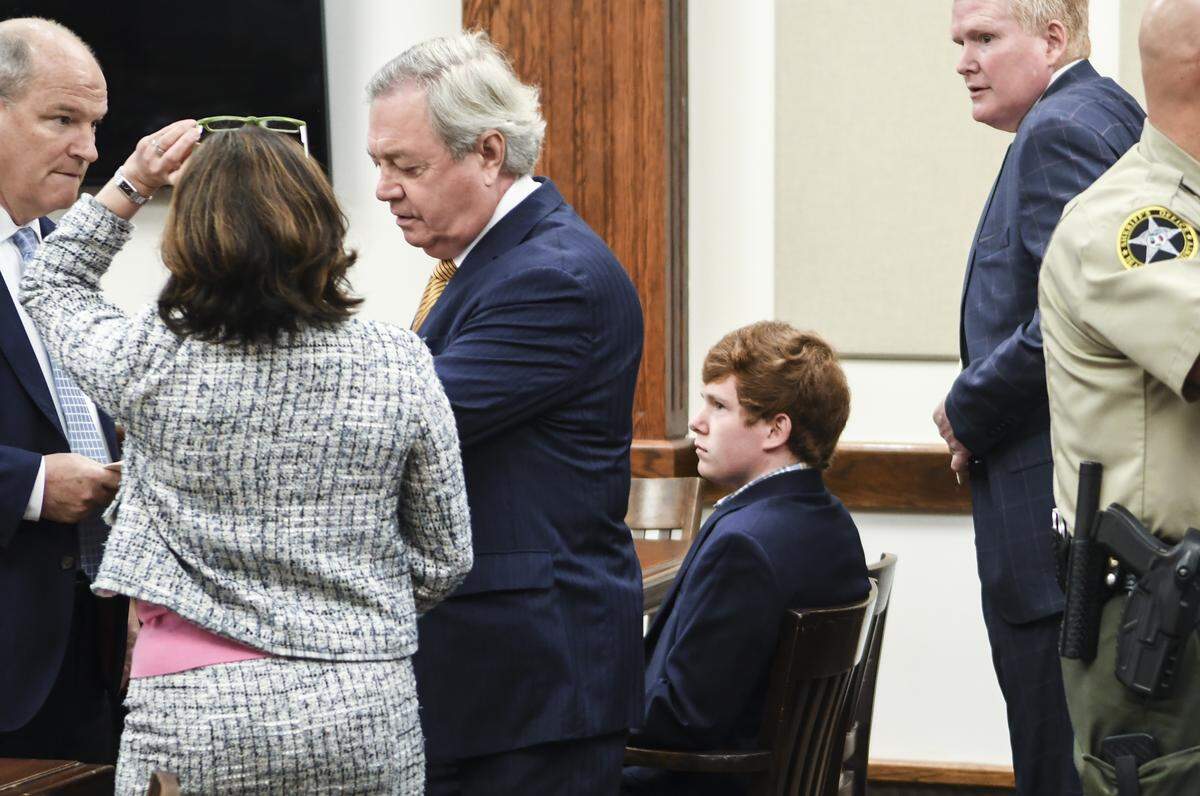 Paul Terry Murdaugh, 20, sitting, waits as his defense attorneys, from left, Jim Griffin and state Sen. Dick Harpootlian, talk with Megan Burchstead, a prosecutor with the S.C. Attorney General’s Office, middle, on the morning of Monday, May 6, 2019 in the Beaufort County Courthouse, as his father, Alexander Murdaugh, right, waits. Paul Murdaugh pleaded not guilty to all three felony counts and went free on a recognizance bond of $50,000 set by state Judge Steven John.