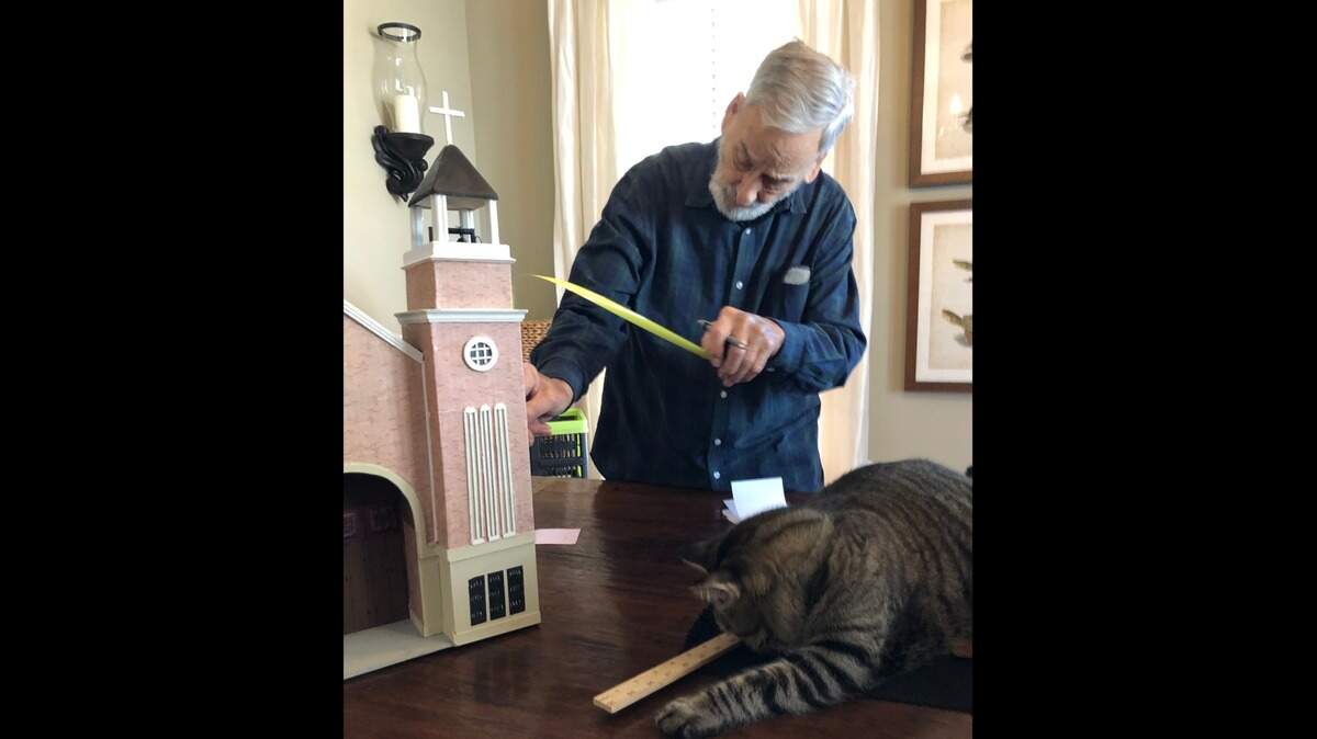 Darrell Schuman, 79, of Beaufort measures a model of St. Peter’s Catholic Church with his cat.