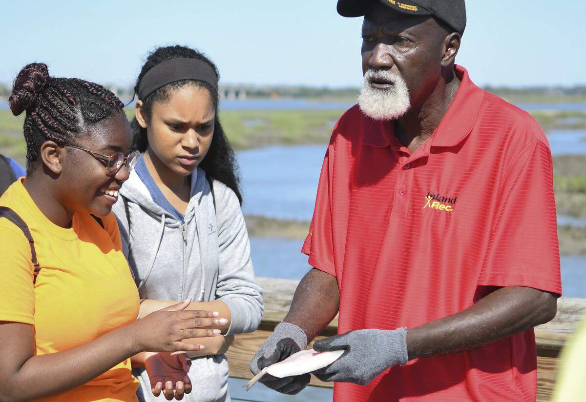Native Hilton Head Islander Ben Green, right, convinces Caitlyn Edwards, left, and Jenascia Peleti that they’ll need to learn to clean a fish if they plan on eating after their hours-long, hands-on class at Squire Pope Community Park.