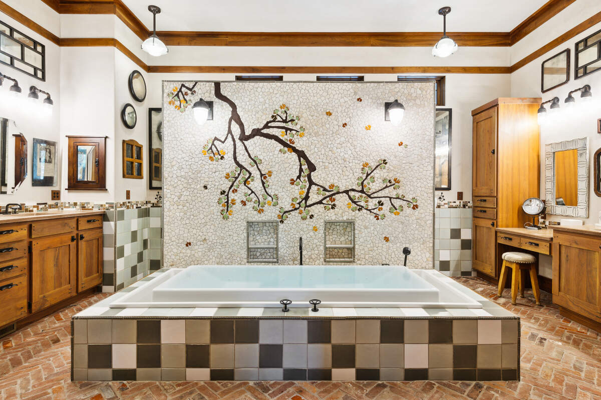 A view of the tile tree mural, which serves as the focal point for the spa-like primary bathroom, found within 36 Plumbridge Circle on Hilton Head Island, SC.