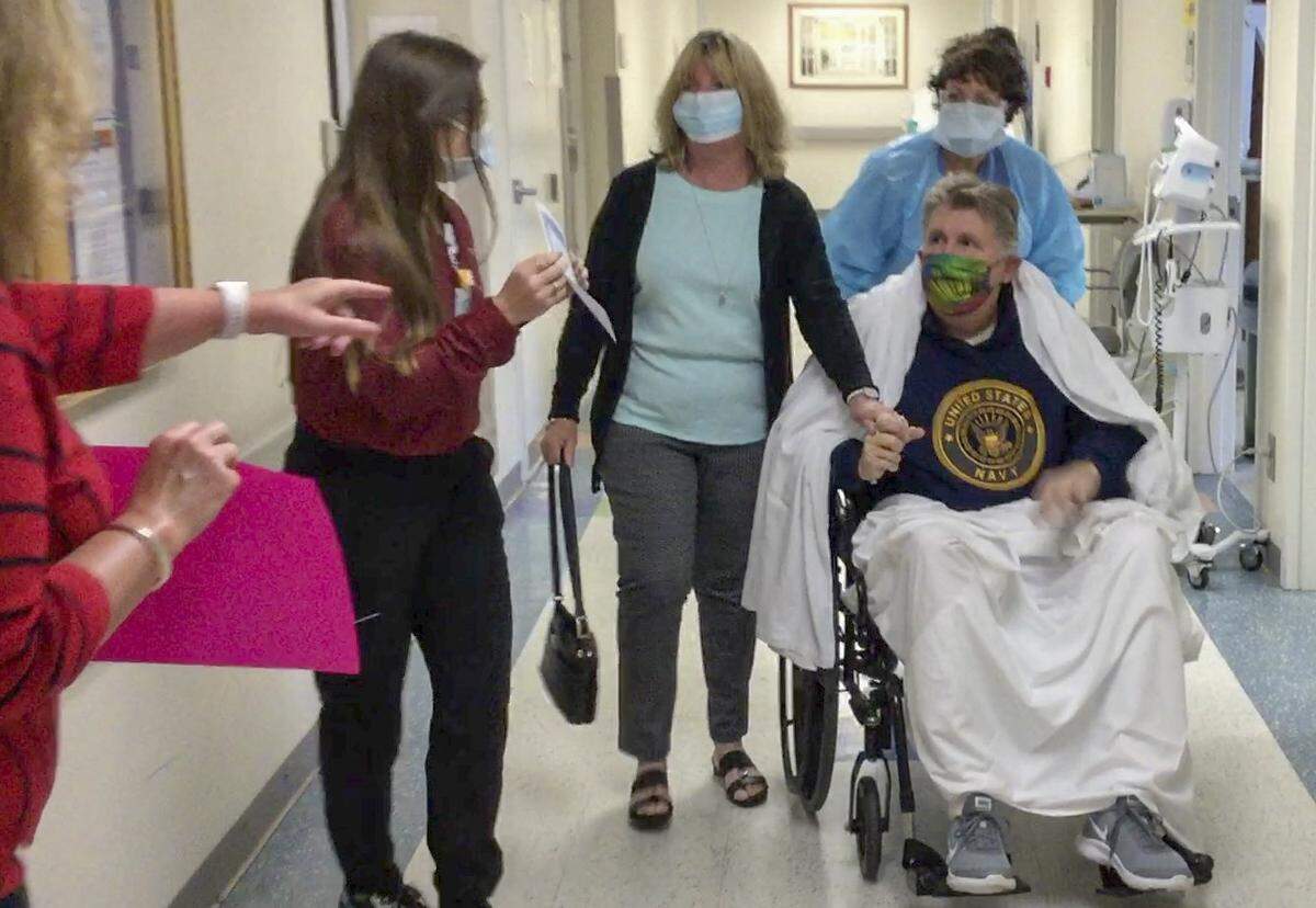 Beaufort residents David Jackson, seated, a survivor of COVID-19, is pushed down the hallway on Wednesday, April 15, 2020 after being treated for the coronavirus at Beaufort Memorial Hospital as his wife, Rebecca Jackson, third from left, holds his hand. David Jackson left the hospital after a months long battle with the coronavirus.