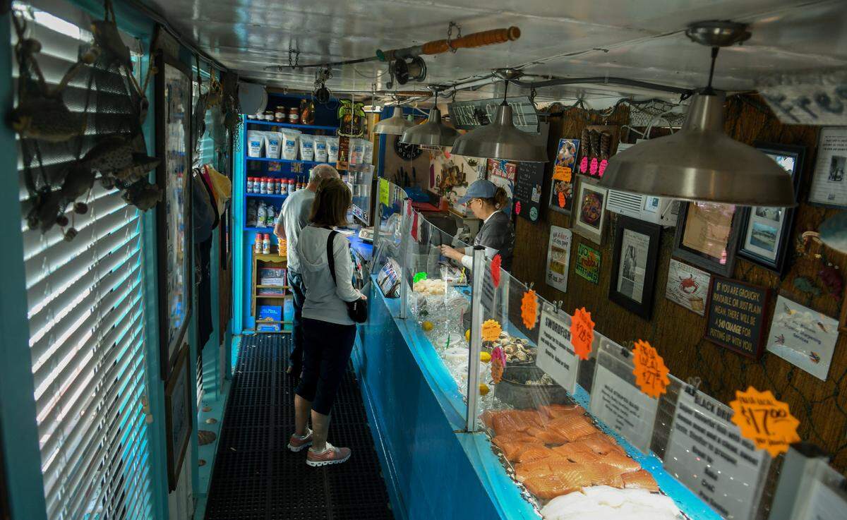 Customers place their orders on Friday, March 24, 2023, with employee Colleen Wooby at Benny Hudson Seafood on Hilton Head Island.