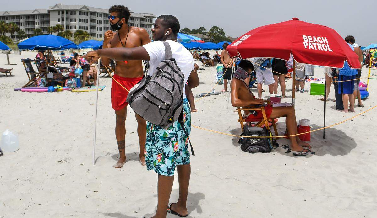 A beachgoer asks a Shore Beach Service lifeguard about a rental on Saturday, June 27, 2020 on the beach of Hilton Head Island. Lifeguards must wear a face covering while on the beach and they maintain social distancing by marking off their lifeguard stands with a boundary rope.