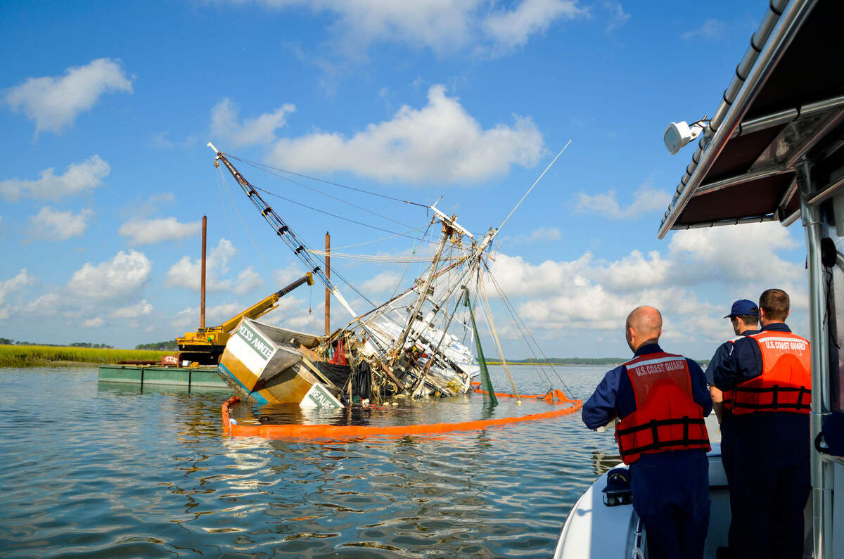 Members of the U.S. Coast Guard watch as divers work to remove oil from the May River.
