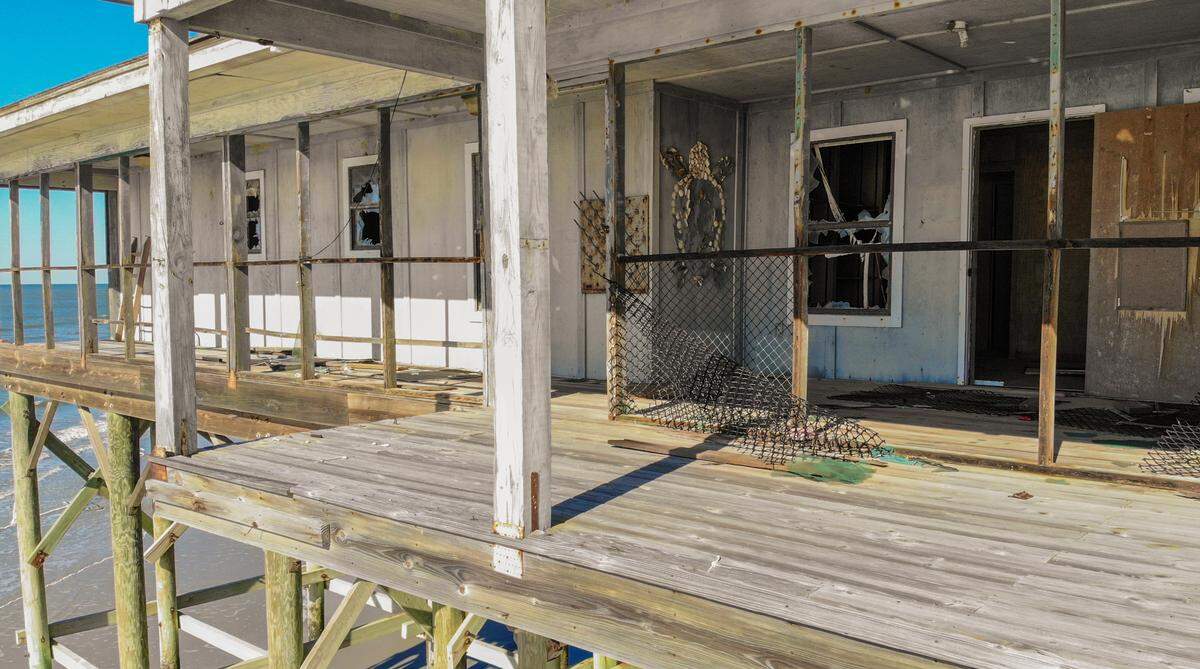 Once accessible with a stairway from the beach, the front door of the Pritchards Island laboratory used for coastal research, as seen in this drone photo taken on April 8, 2022. The lab is inaccessible due to erosion on Pritchards Island. While all of the windows have been smashed, a wall at the front door still bears artwork of a loggerhead turtle made of seashells.