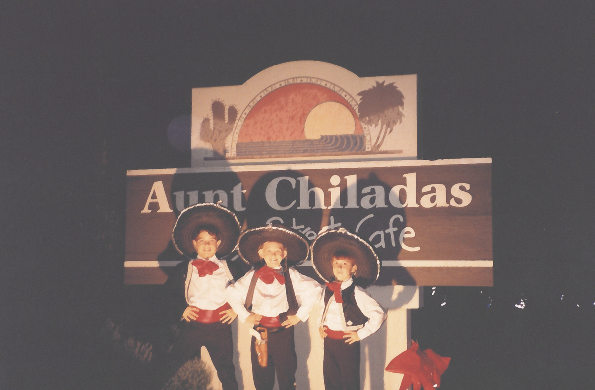 Three boys pose in front of the Aunt Chilada’s sign.