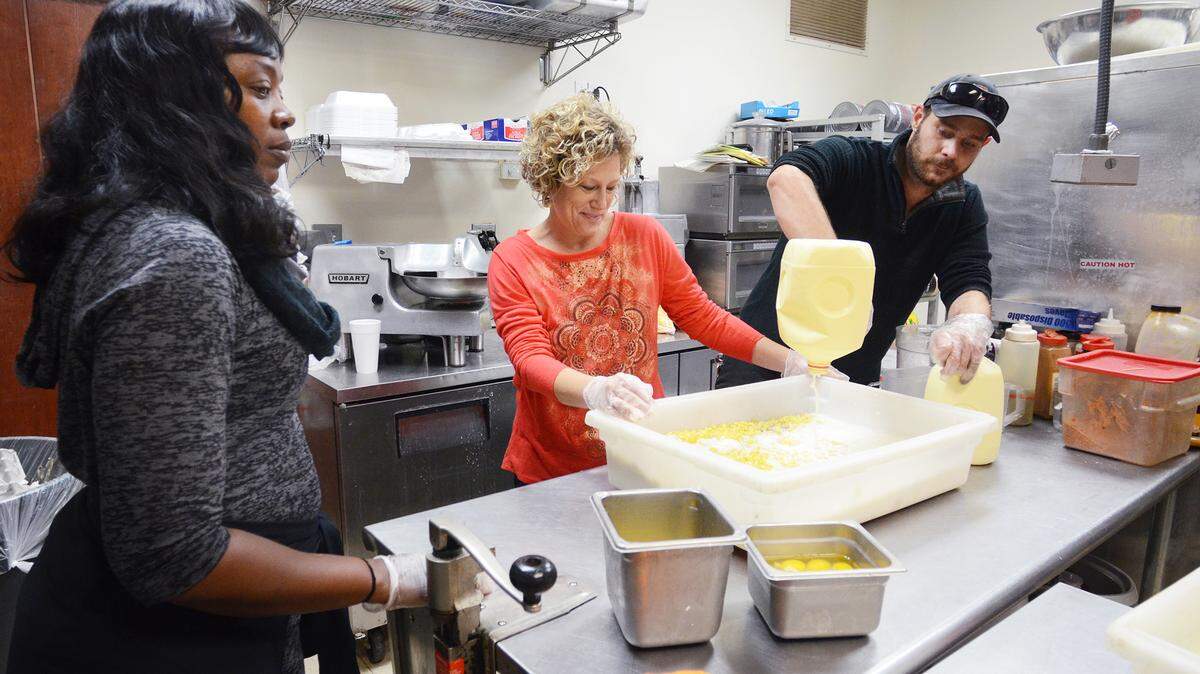 From left, Yolanda Smith, mother of former college and pro football player Marcus Lattimore and vice president of the Marcus Lattimore Foundation, watches as volunteer Jennifer Tapp and restaurant employee Robert York prepare a batch of macaroni and cheese for Thursday's free community Thanksgiving dinner at The Bar-B-Q Grill in Ridgeland on Wednesday. The dinner, for up to 1,000 Jasper County residents -- an outreach effort of the Foundation -- will take place at the restaurant from 11 a.m. to 2:30 Thursday. The foundation will also deliver meals to senior citizens at home.