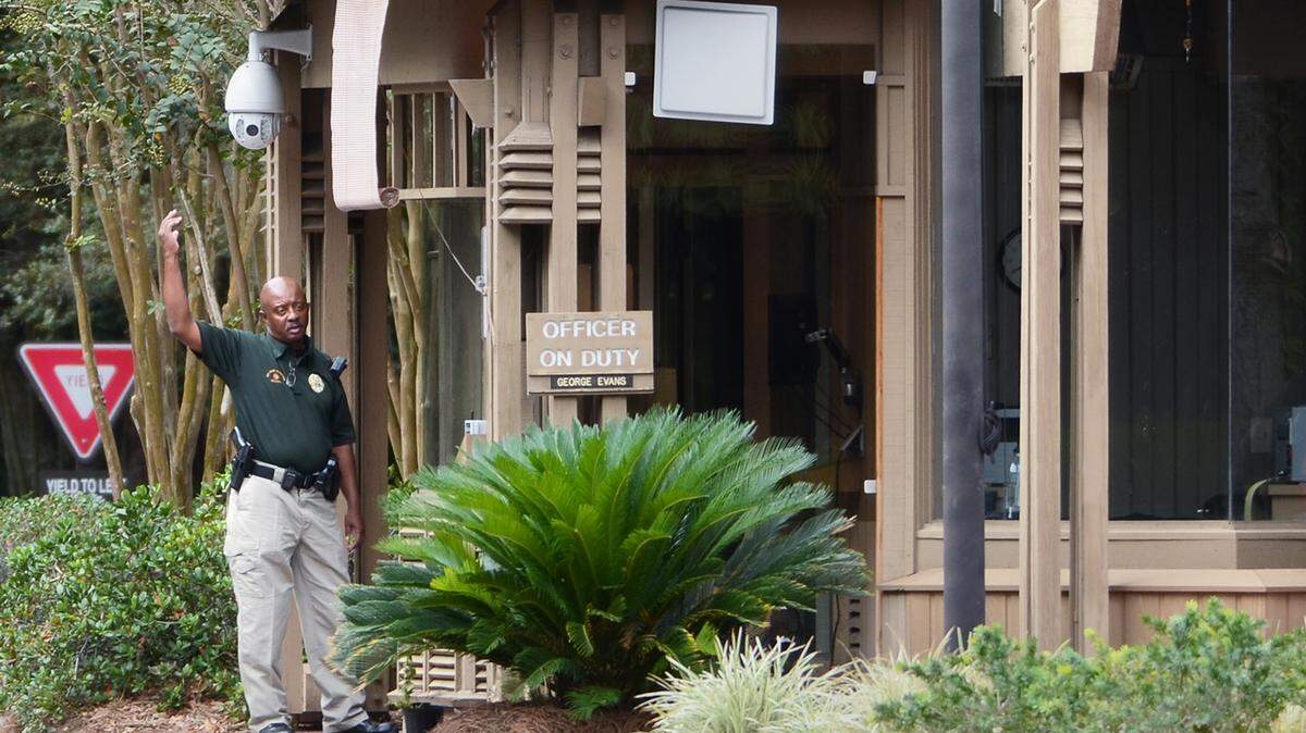 An armed security officer waves a vehicle through the Greenwood gate into Sea Pines on Oct. 21, 2015.