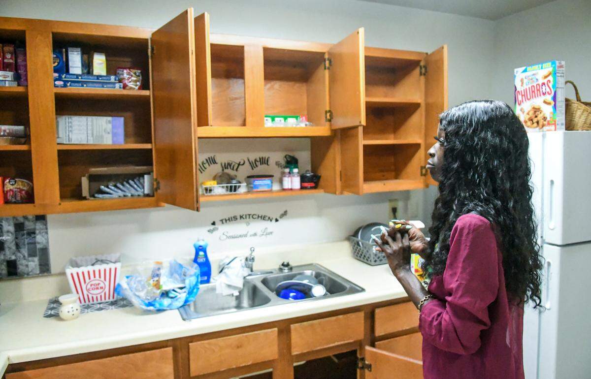 Tiffany Glover, a single mother and resident of Sandalwood Terrace apartments opens all of the kitchen cupboards on Wednesday, Oct. 21, 2020 in her apartment on Hilton Head Island. Glover only keeps packaged items in the cupboard including microwavable popcorn for her son because of the roach infestation.