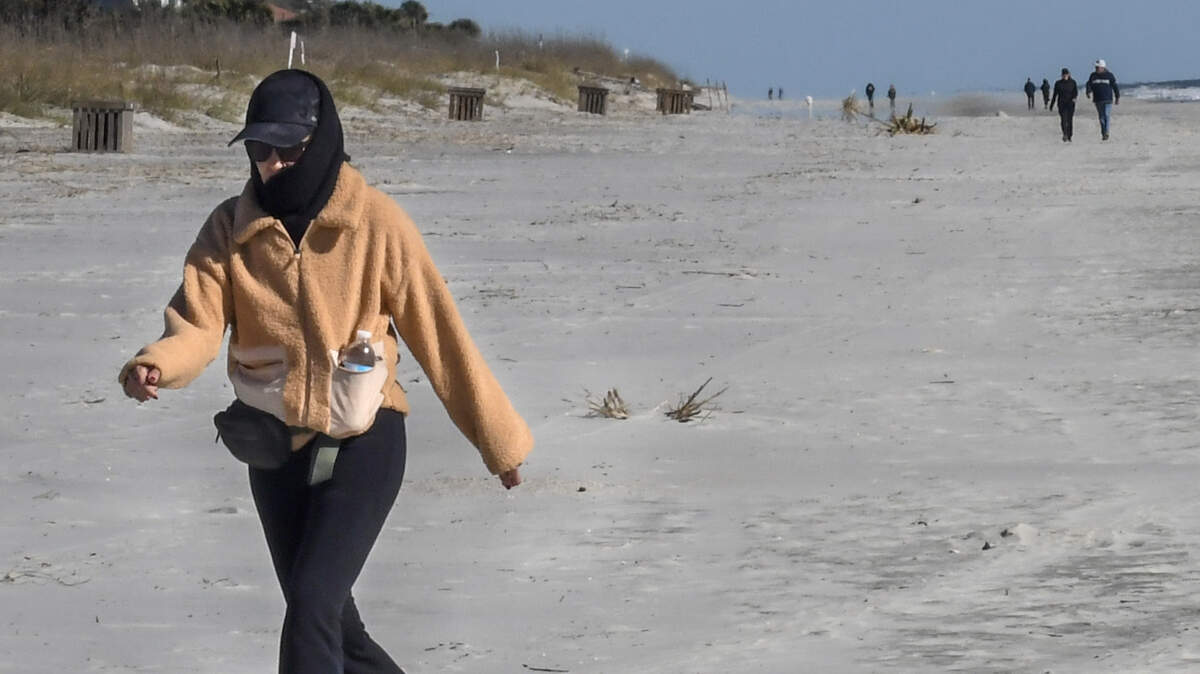 A woman walks briskly along the beach near Hilton Head Island’s Coligny Beach Park on the frigid morning of Tuesday, Jan. 7, 2025, as a polar vortex makes its way from the high Arctic to parts of the deep South in the first weeks of the new year.