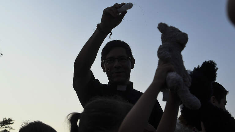 Family brings a chicken to the blessing of animals at Beaufort County Catholic school