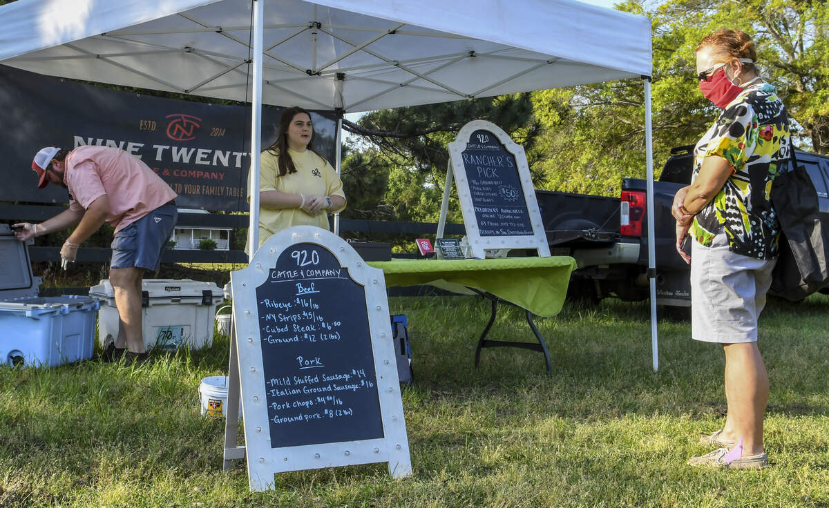 A customer contemplates the beef and pork for sale as as Riley Thompson, center, explains some of the specials while Jarrod Creasy, left, owner of Nine Twenty Cattle & Company, looks over the inventory on Tuesday, April 7, 2020 at Hilton Head Island’s farmers market at Honey Horn.