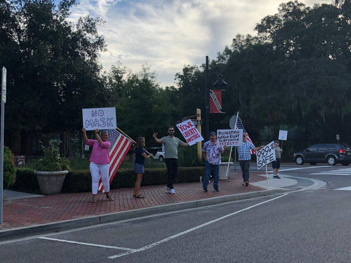 A small group of protesters hold signs and wave at passing cars Tuesday, Sept. 8 at the four-way stop at May River Road and Boundary Street in Old Town Bluffton. The group was protesting Bluffton’s mask ordinance. 