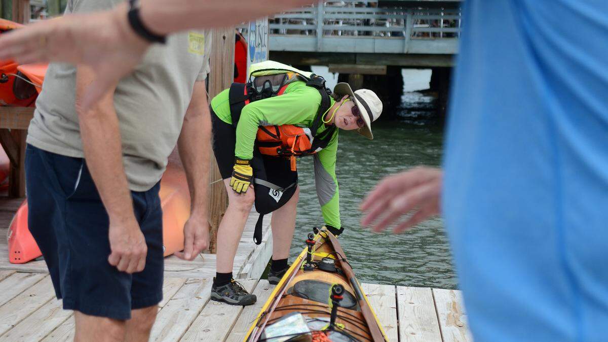 Deb Walters, of Troy, Maine, tries lift her kayak into the water with help from several bystanders at the dock at Hudson's Seafood House On The Docks on Oct. 13, 2015, before heading to the next stop on her journey, Daufuskie Island.  Walters, who stopped on Hilton Head Island to rest, is kayaking from Maine to Guatemala to try and raise money and awareness for kids who live in the garbage dump there.