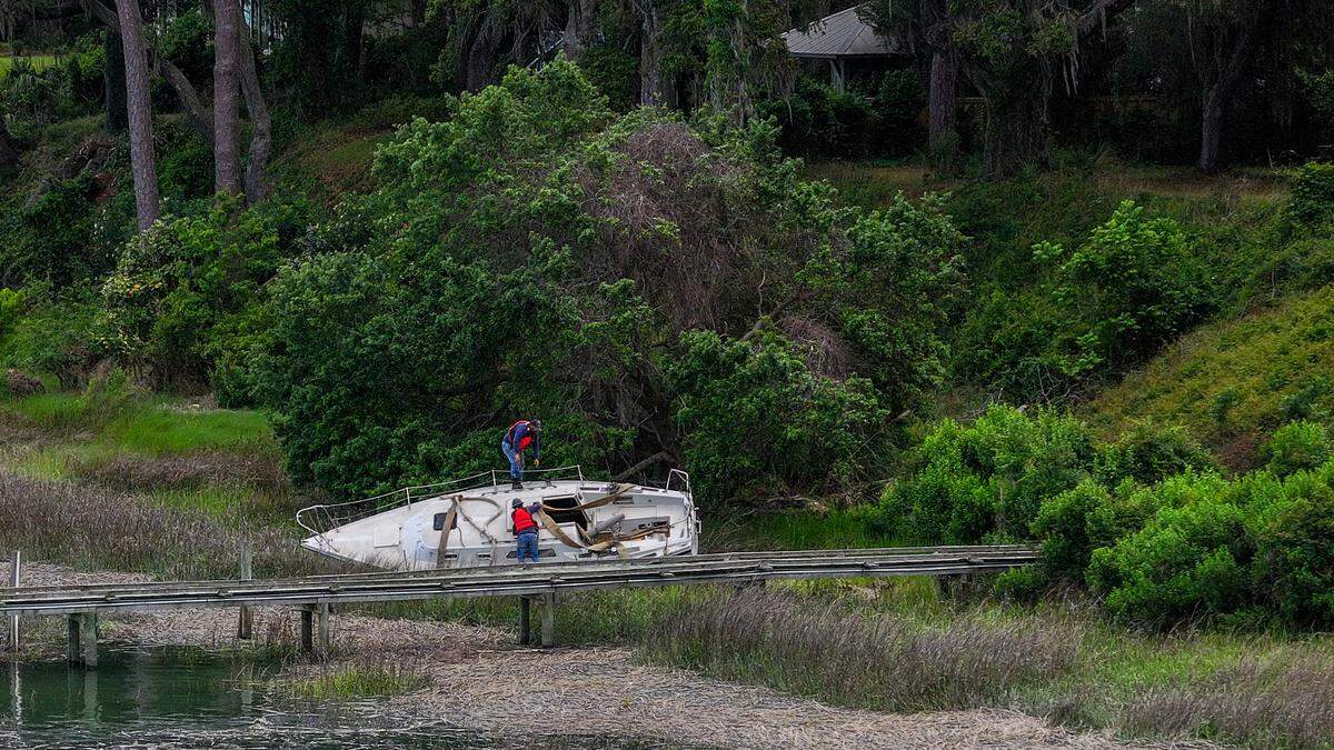 Workers with O’Quinn Marine prepare a small boat with strappings and rope in order to pull it from the bank of the Beaufort River on the evening of April 23, 2025, in Historic Beaufort. Five boats were beached after they were ripped from their moorings during Tropical Storm Helene in 2024.