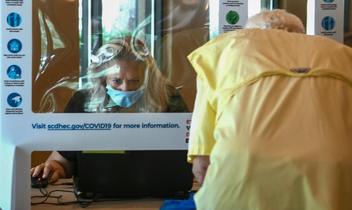 Working behind a cardboard and plastic lined sneeze guard, first-year poll worker Sonia Geiss checks a voter in just before noon on Tuesday, June 9, 2020, at the Arts Center of Coastal Carolina on Hilton Head Island. Geiss said she read that that poll workers were needed and wasn’t concerned about the pandemic. “You see so many tourists here you have to live your life,” Geiss said after assisting about 100 voters since opening in the morning. “But, I do stay away from the crowds.”
