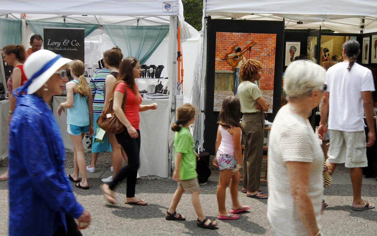 Patrons walk in front of the Lory & Co. tent, of Austin, T.X., left, and artist Elginia McCrary, of Chesapeake, V.A., during the sixth annual Hilton Head Island Art Festival at Shelter Cove Harbour on May 25, 2014.